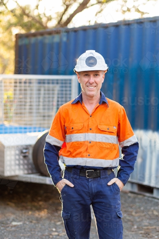 Portrait of happy smiling handyman tradie with protective headwear and high vis workwear - Australian Stock Image