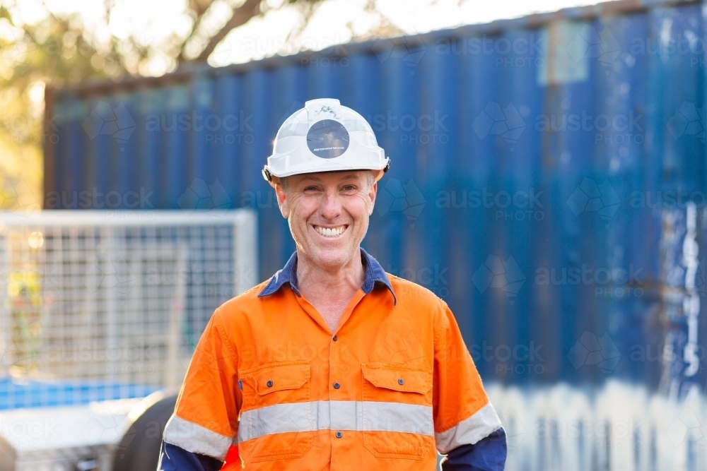 Portrait of happy smiling handyman tradie with protective headwear and high vis workwear - Australian Stock Image