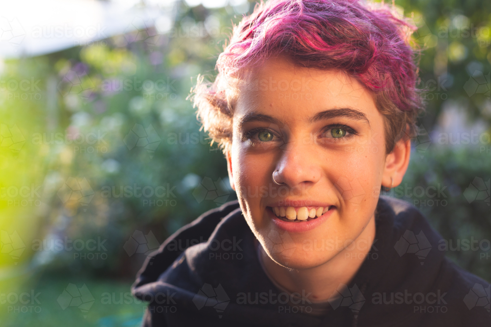 Portrait of happy, smiling teenage girl with short hair in vibrant, natural outdoor setting - Australian Stock Image