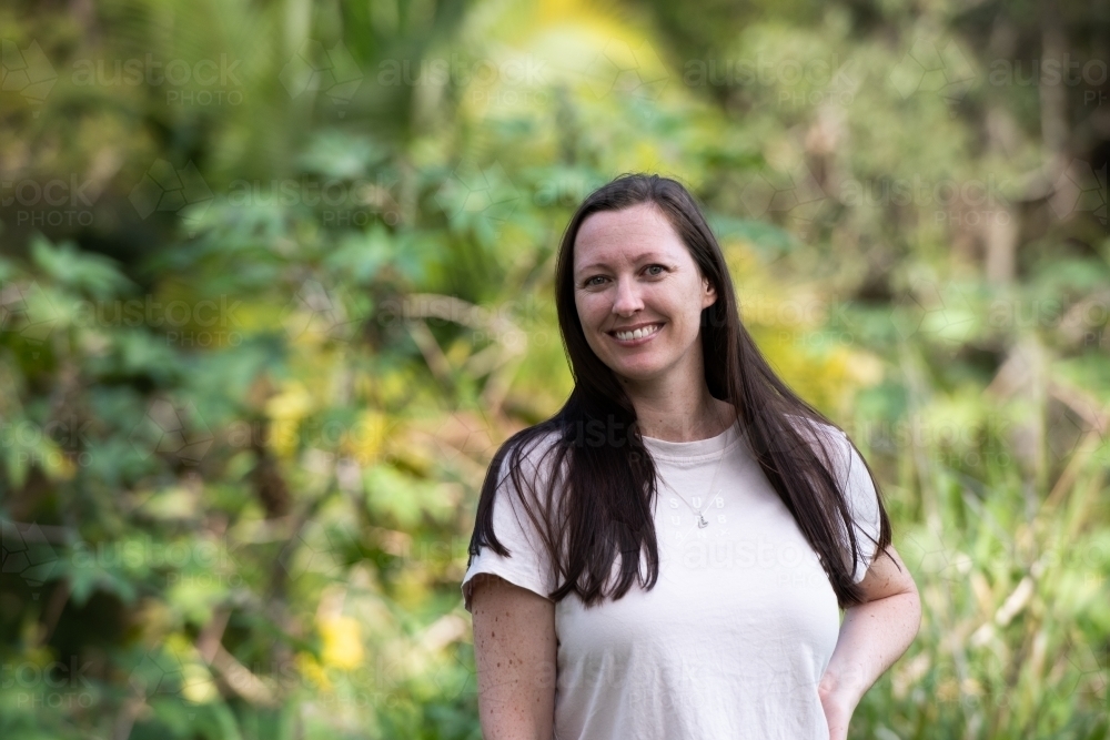 Portrait of happy woman with long dark hair and a big smile and blurred background - Australian Stock Image