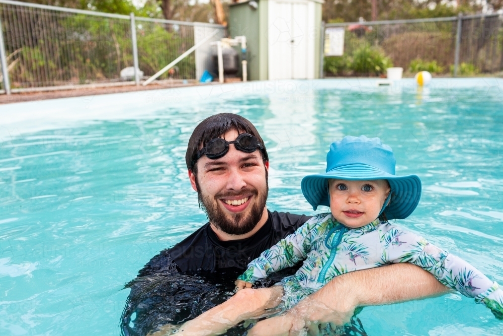 Portrait of little girl and dad in backyard swimming pool - Australian Stock Image