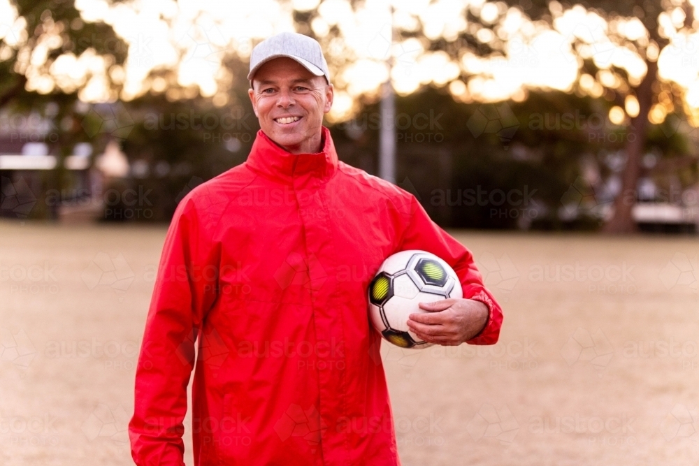 Portrait of male football coach wearing a cap and smiling proudly - Australian Stock Image