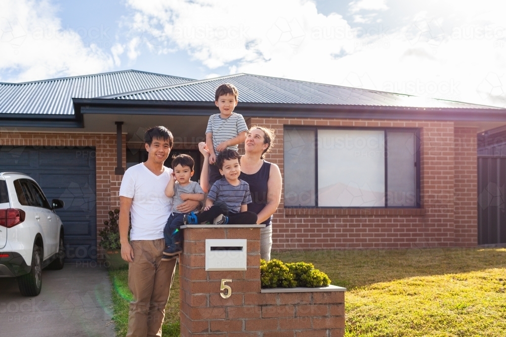 portrait of mixed race Chinese Australian family outside home with kids sitting on mailbox - Australian Stock Image