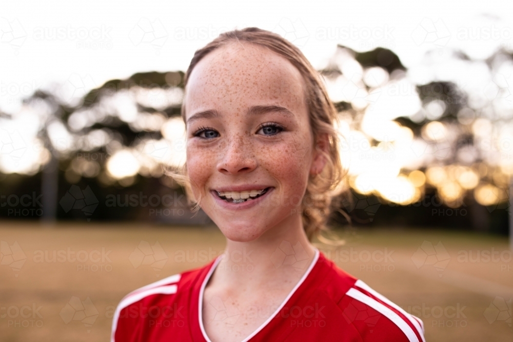 Portrait of single tween girl football player wearing a red sports uniform - Australian Stock Image