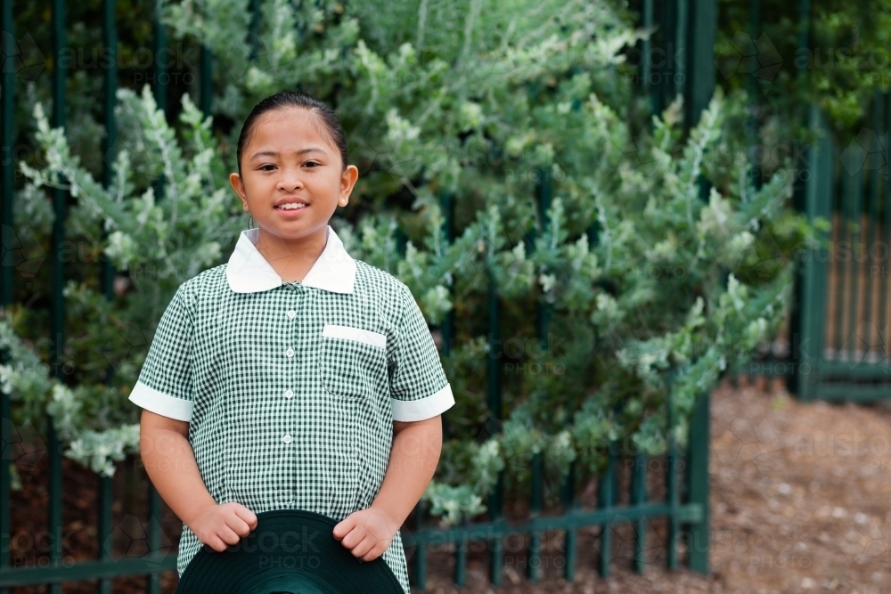 Portrait of smiling public school kid in green dress holding her hat - Australian Stock Image