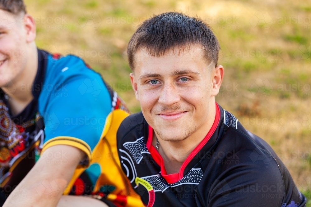 Portrait of teen footy player sitting on sports field - Australian Stock Image