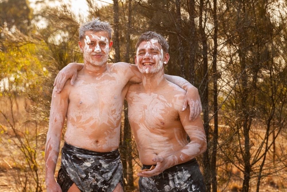 Portrait of two smiling First Nations young men who are cousins with arms over shoulders - Australian Stock Image