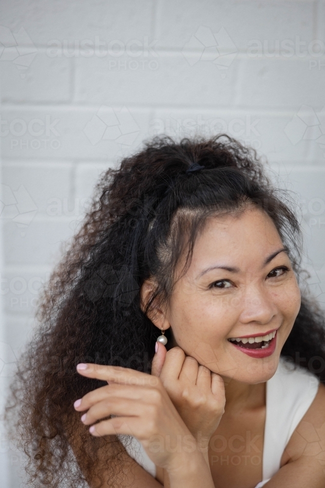 Portrait of woman smiling against blank wall - Australian Stock Image