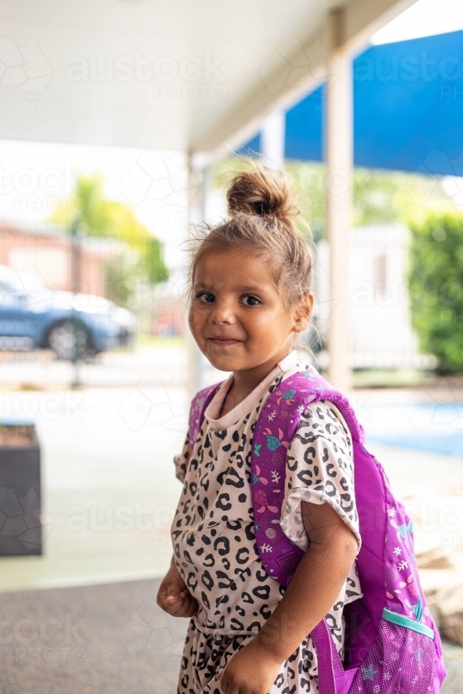 Portrait of young Aboriginal girl at preschool with backpack - Australian Stock Image