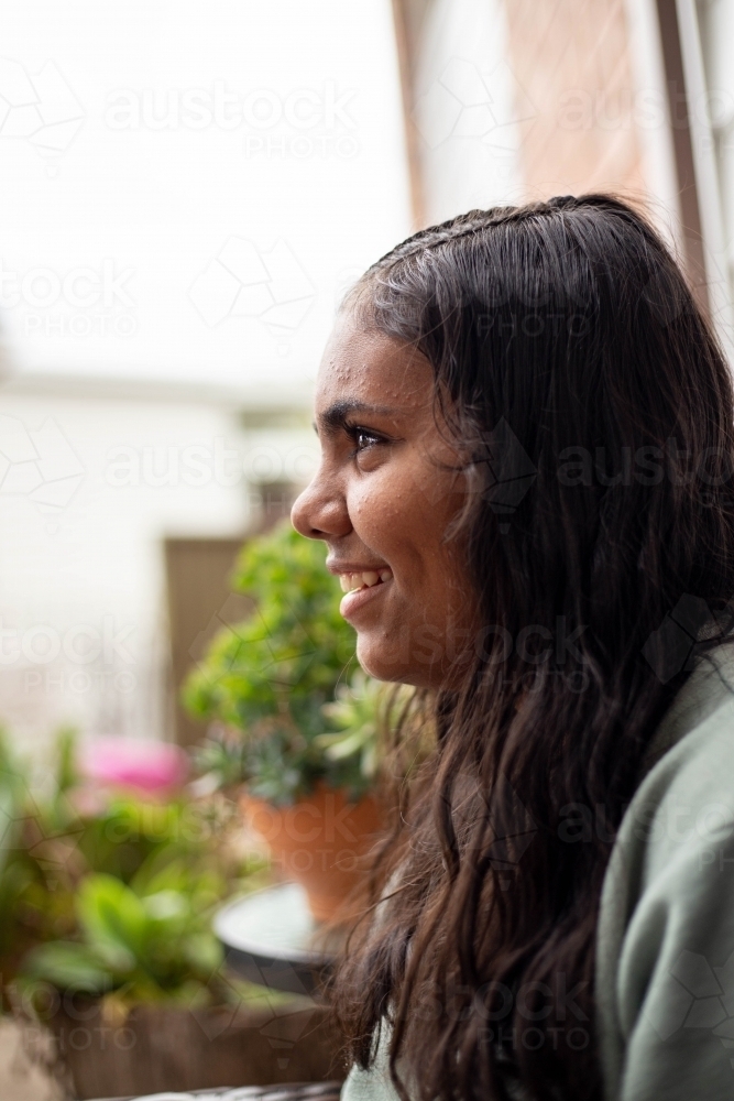 Portrait of young Aboriginal woman sitting outside - Australian Stock Image