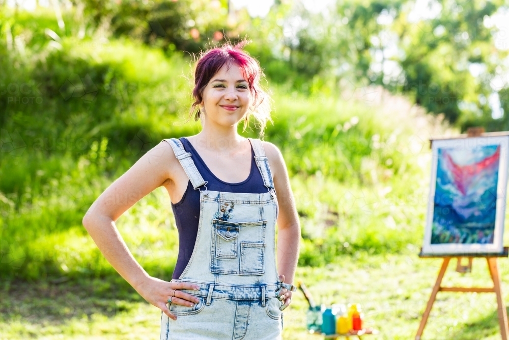 Portrait of young artist with hands on hips backlit by sunlight - Australian Stock Image