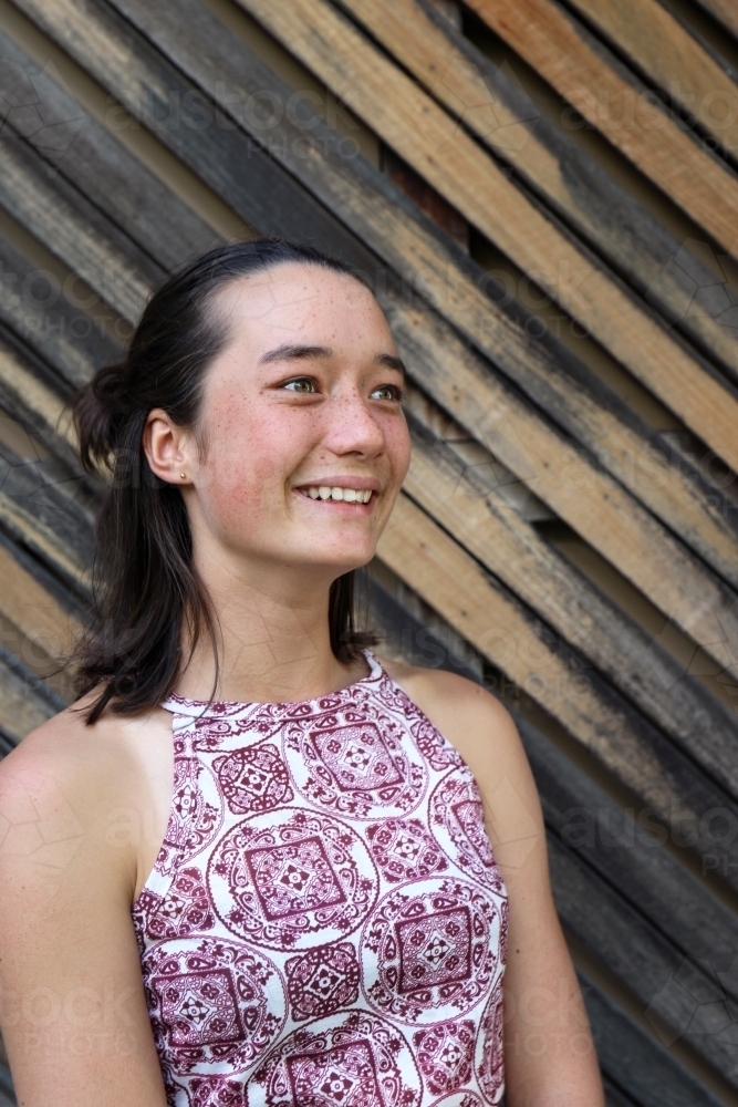 Portrait of young female outdoors with textured wooden background - Australian Stock Image