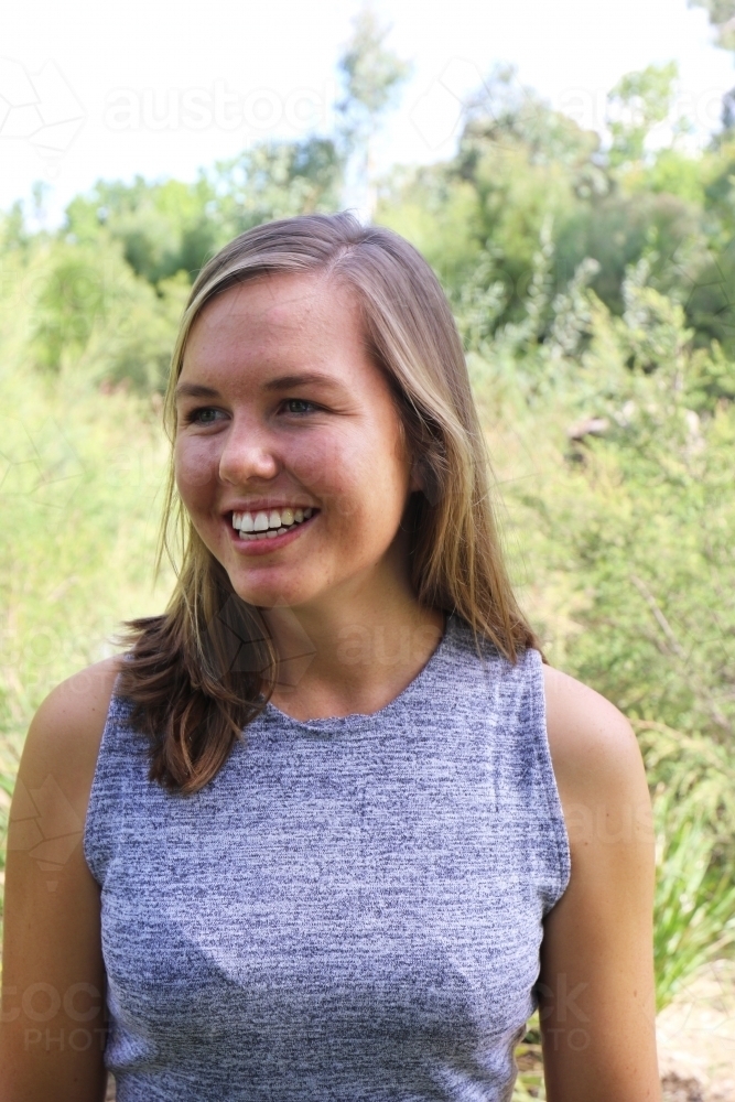 Portrait of young female outdoors with trees in background - Australian Stock Image