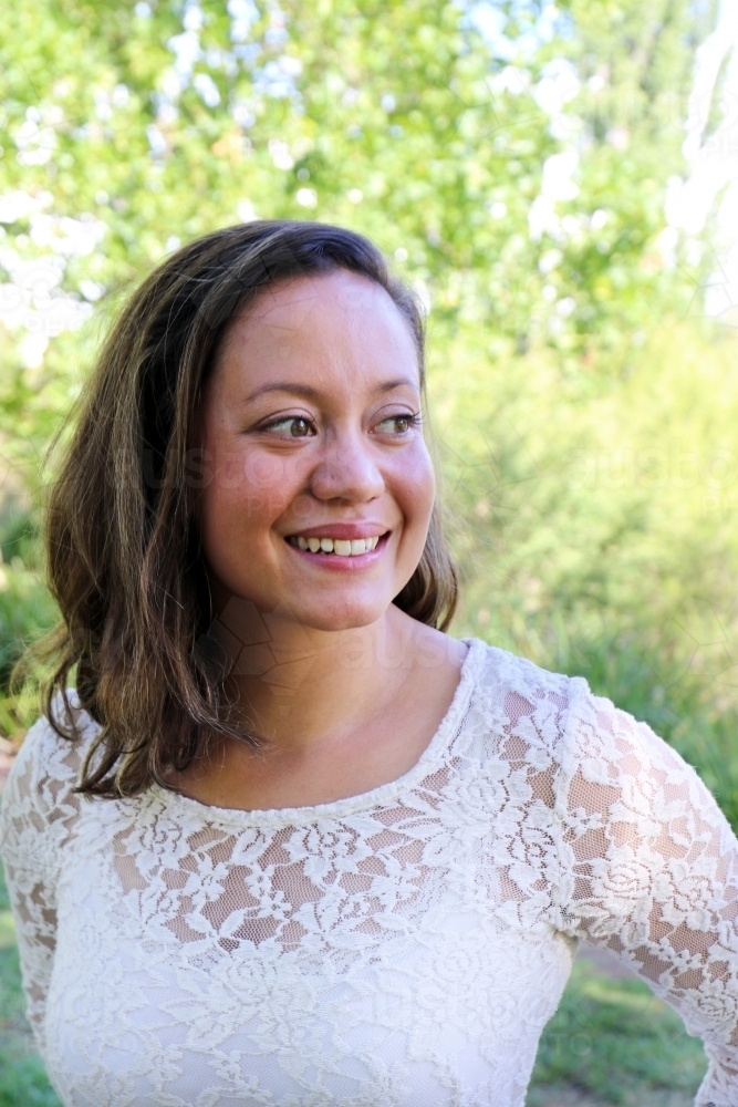 Portrait of young female outdoors with trees in background - Australian Stock Image