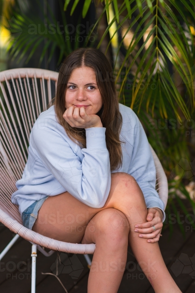 portrait of young teen girl sitting on a chair outside - Australian Stock Image