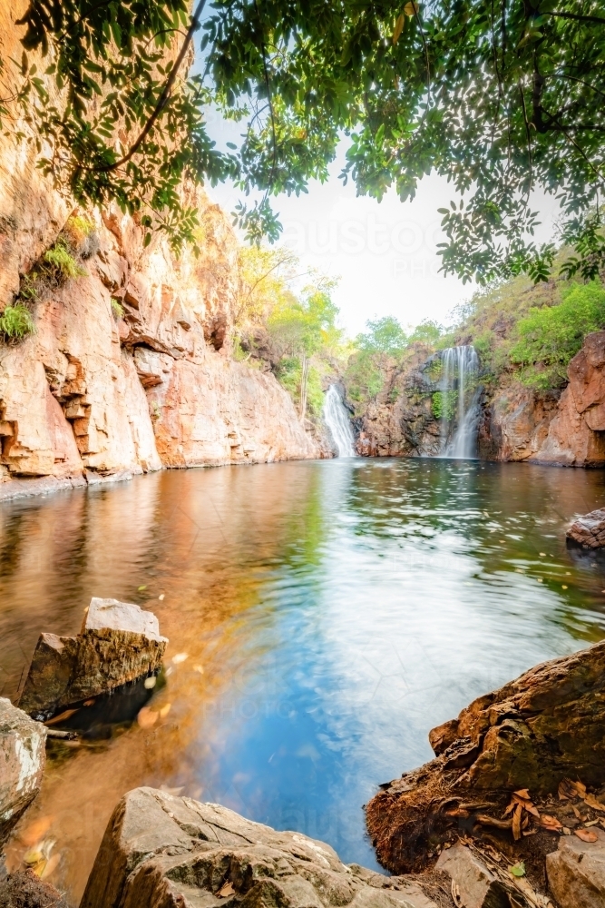 Portrait view of Florence Falls being framed by rocks and overhanging branches - Australian Stock Image