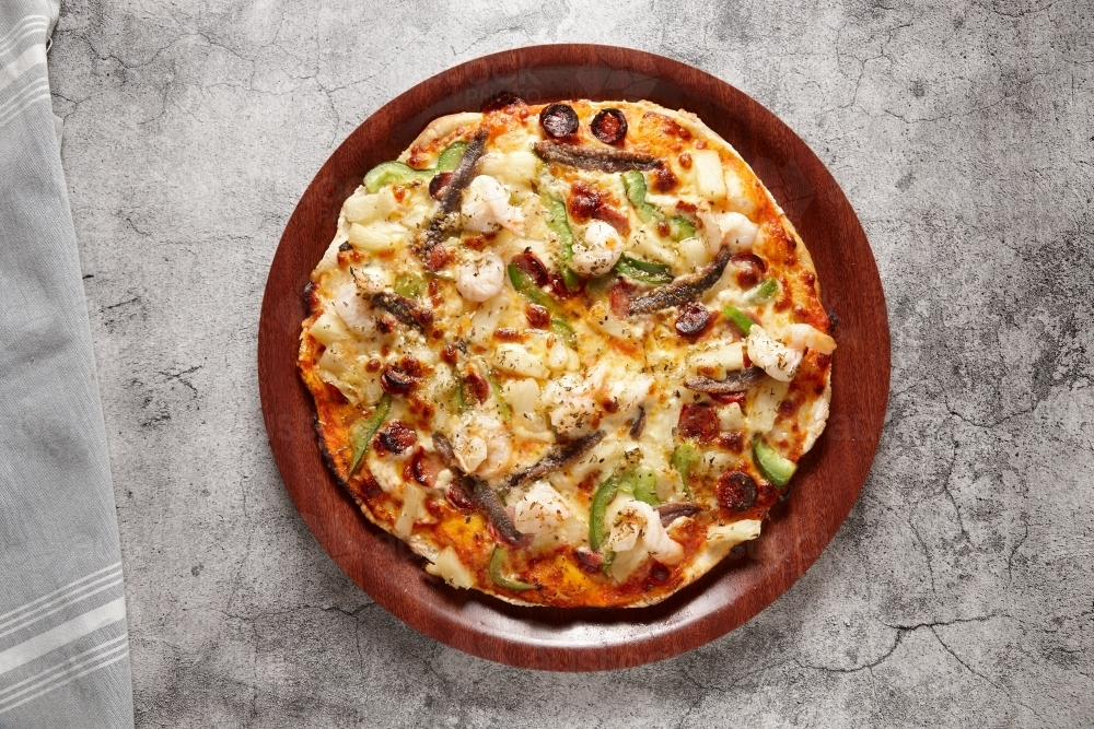 Prawn pizza on wooden plate - Australian Stock Image