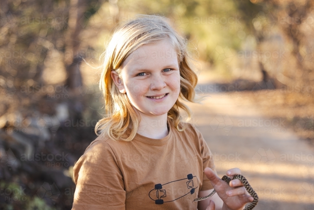 Pre-teen adolescent boy holding pet children's python snake - Australian Stock Image