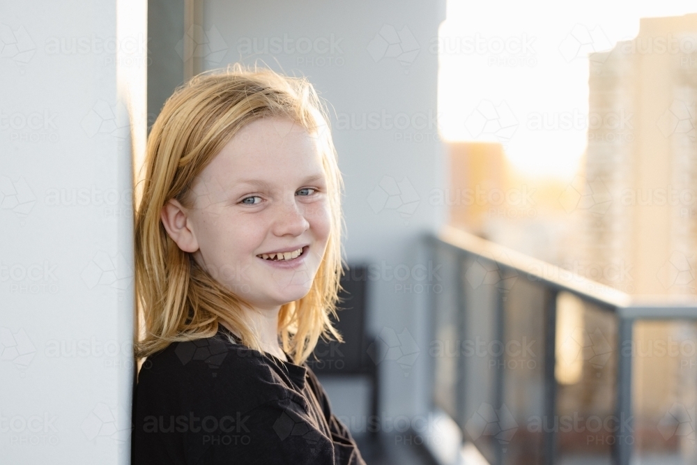 Pre-teen boy leaning against wall on balcony of high rise building on the Gold Coast - Australian Stock Image