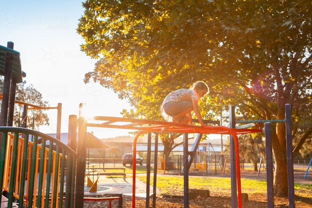 Pre-teen kid climbing on park playground equipment - Australian Stock Image