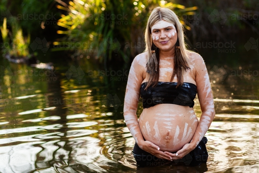 Pregnant Aboriginal Australian woman in sparkling creek water on a summer afternoon - Australian Stock Image