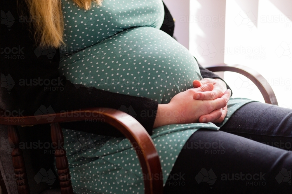 Pregnant woman sitting in rocking chair - Australian Stock Image