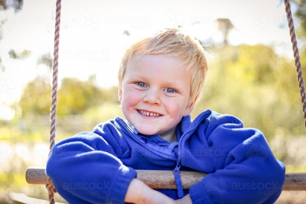 Preschool age child posing on rope ladder swing for kindergarten photos. Portrait of young boy. - Australian Stock Image