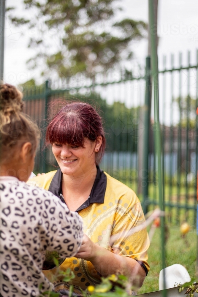 Preschool teacher talking to her student and smiling - Australian Stock Image