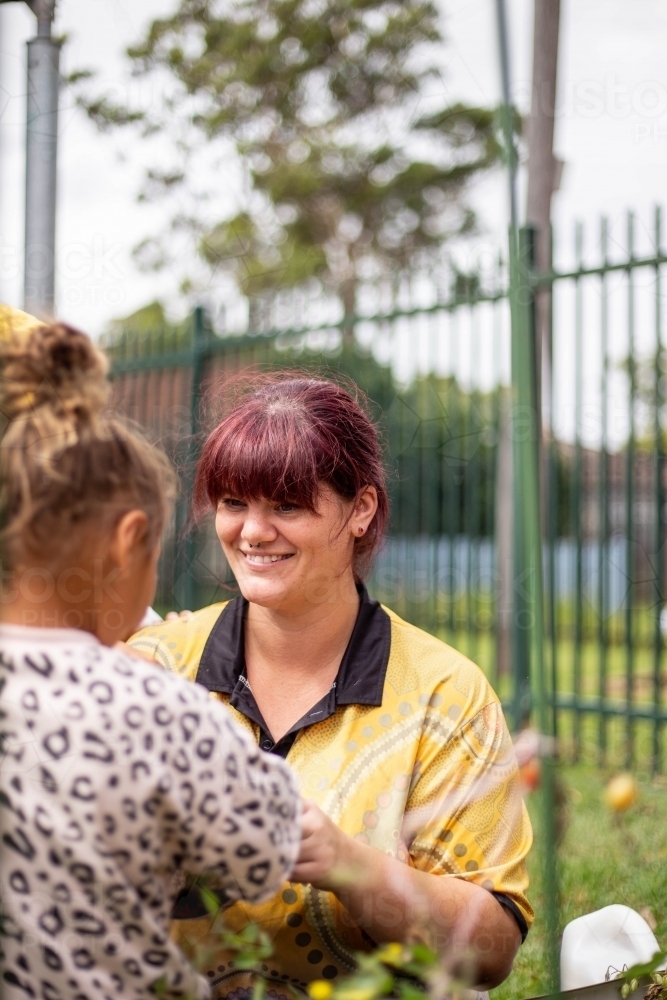 Preschool teacher talking to her student and smiling - Australian Stock Image