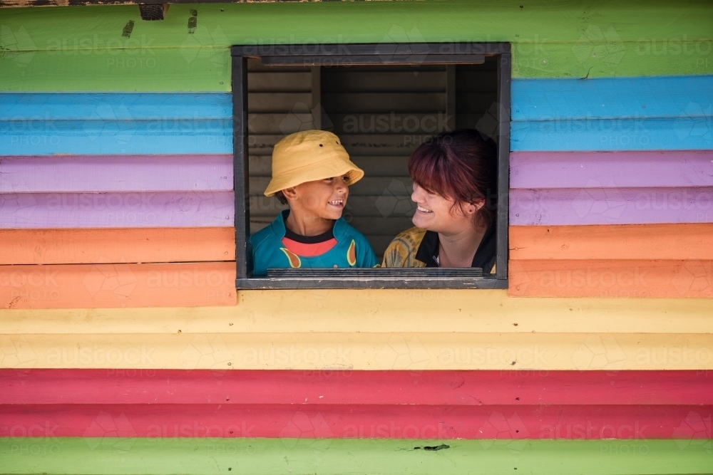 Preschool teacher with young Aboriginal  boy in cubby house window - Australian Stock Image