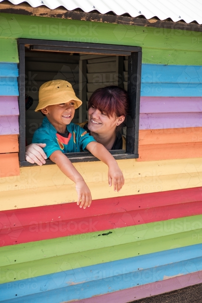 Preschool teacher with young Aboriginal  boy in cubby house window - Australian Stock Image