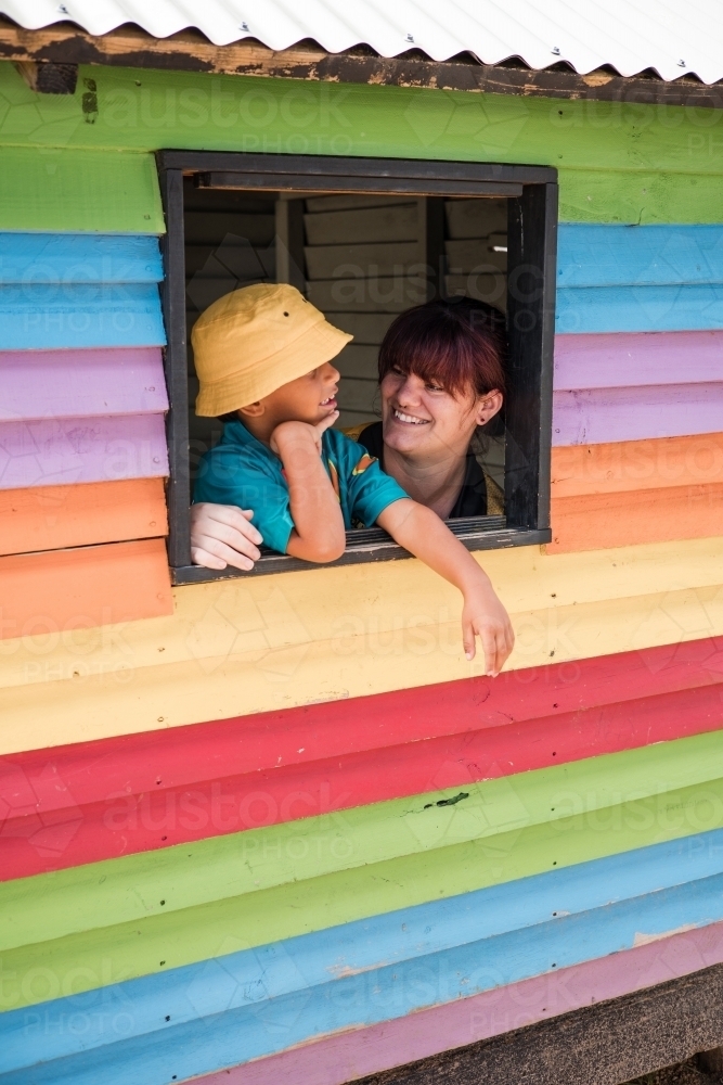 Preschool teacher with young Aboriginal  boy in cubby house window - Australian Stock Image