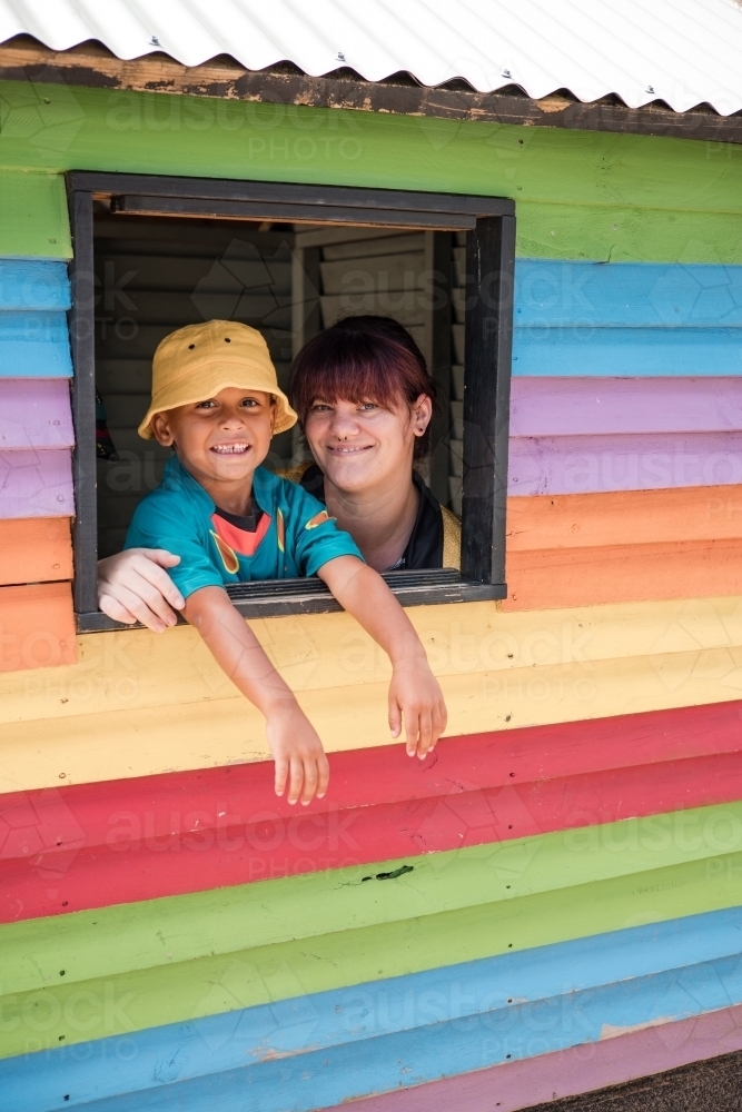 Preschool teacher with young Aboriginal  boy in cubby house window - Australian Stock Image