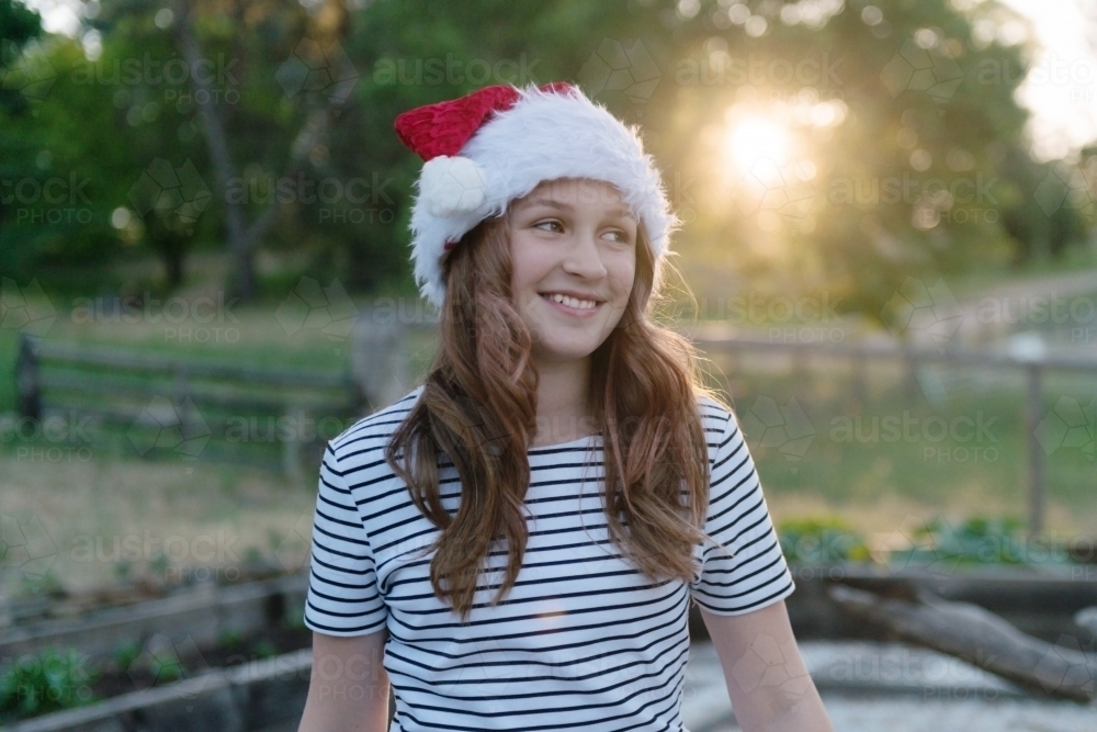 pretty teen girl in Christmas hat, with backlit sunshine - Australian Stock Image