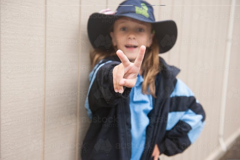 Primary school girl making a happy peace sign to camera - Australian Stock Image