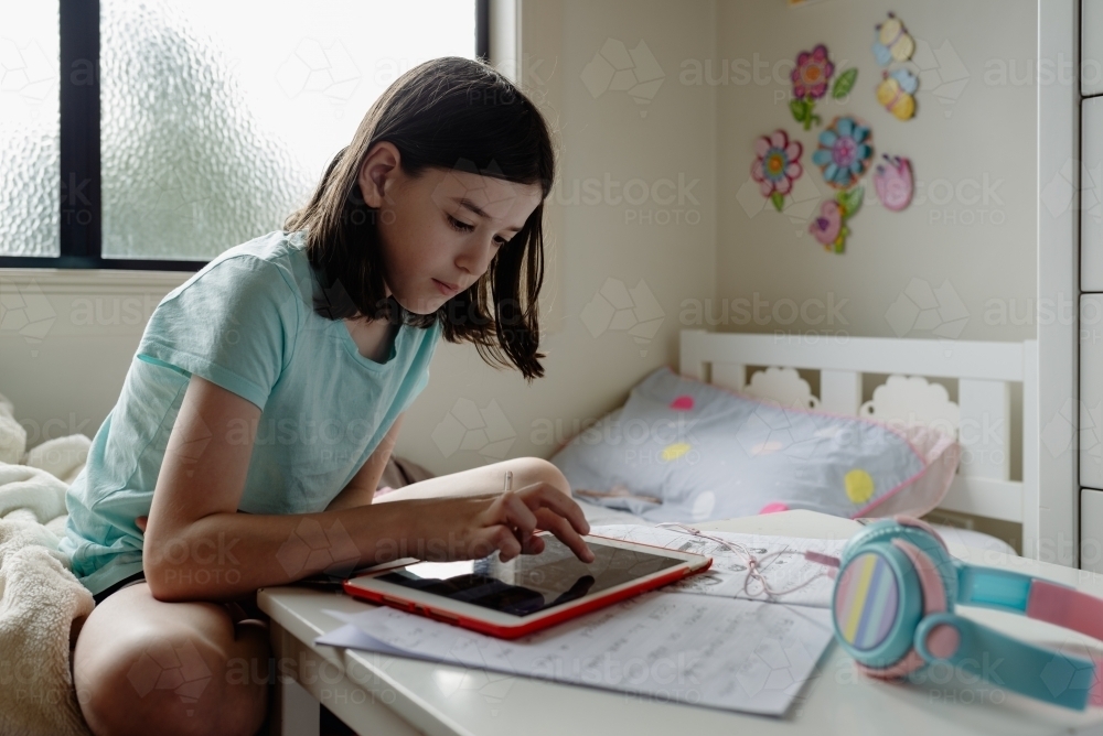 Primary school girl student at home using tablet computer for remote online learning covid-19 2020 - Australian Stock Image