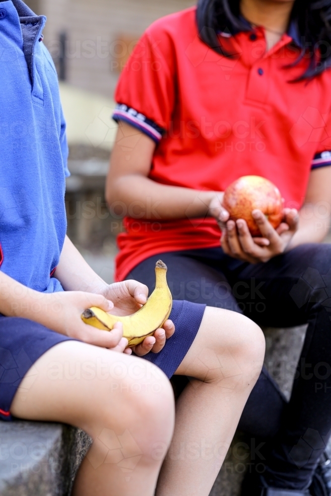 primary school student holding healthy banana for fruit break - Australian Stock Image