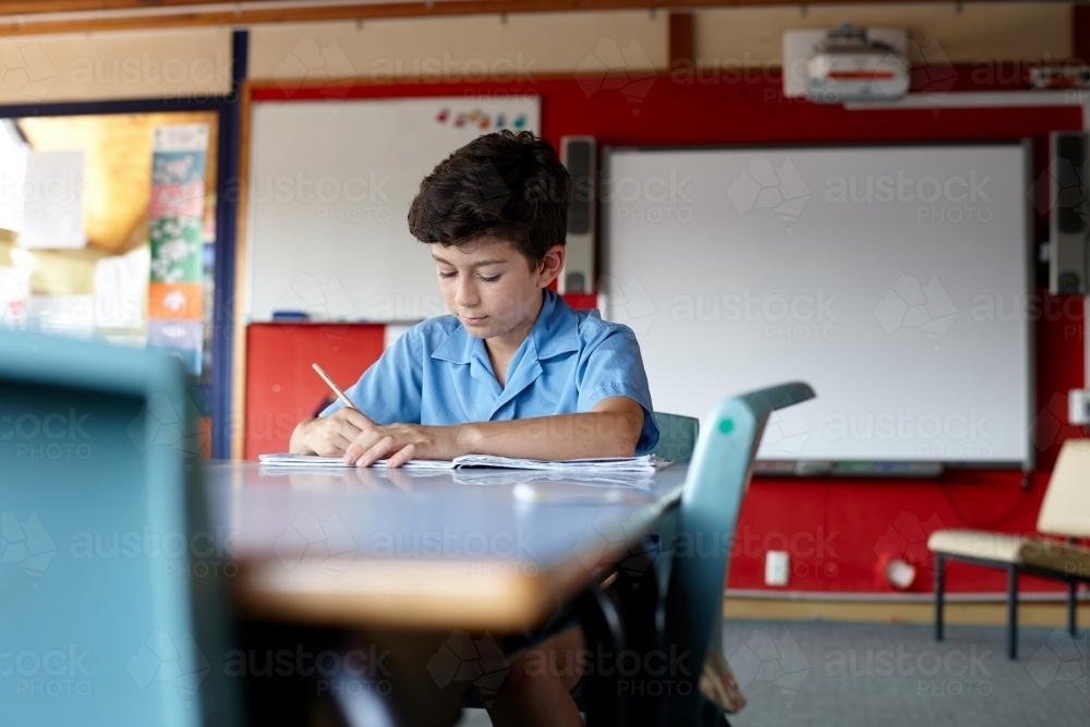 Primary school student in classroom working on homework - Australian Stock Image