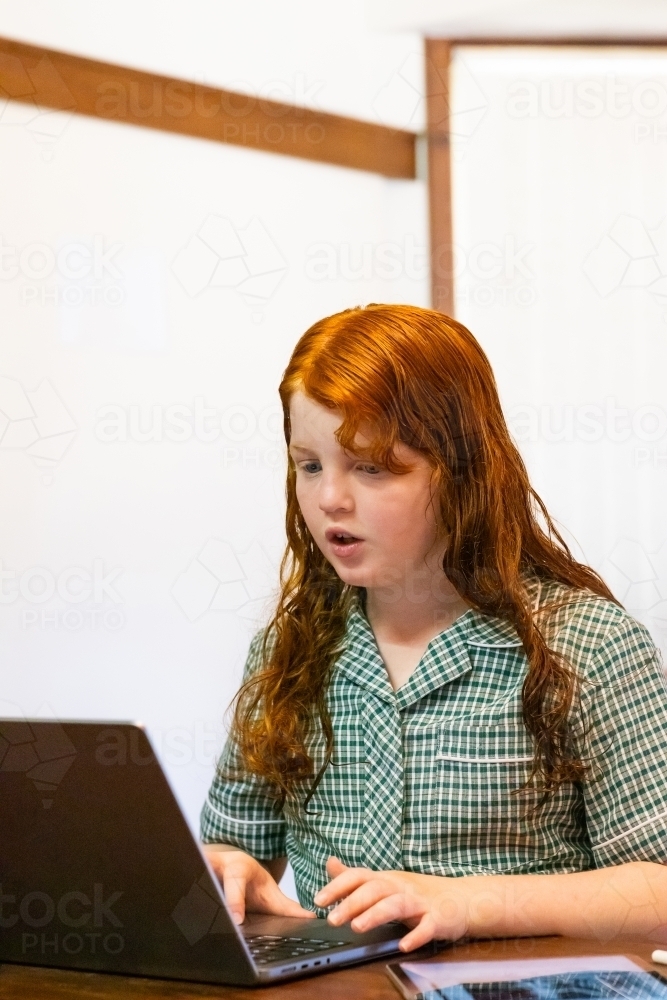 primary school student in school uniform doing work on laptop computer - Australian Stock Image