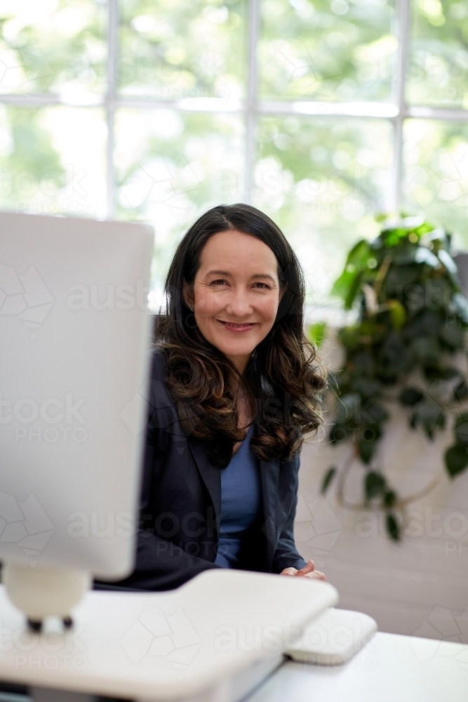 Professional business woman sitting at a computer in an office studio - Australian Stock Image