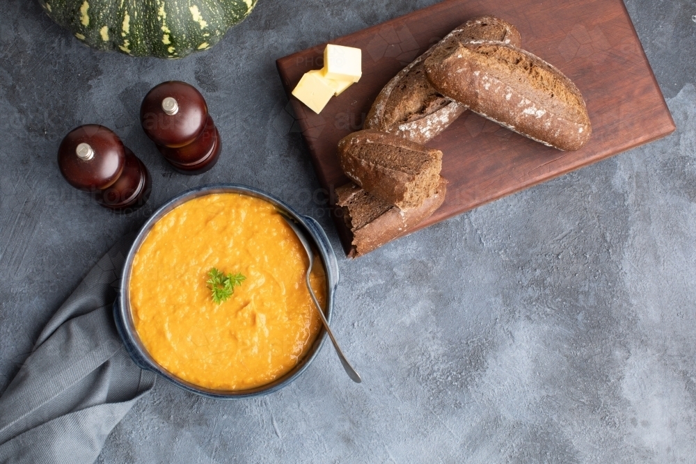 Pumpkin soup scene on dark blue kitchen bench with whole pumpkin - Australian Stock Image