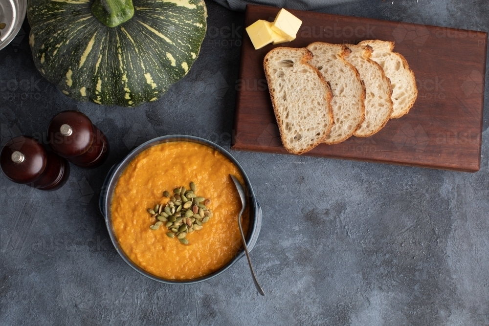 Pumpkin soup scene on dark blue kitchen bench with whole pumpkin - Australian Stock Image