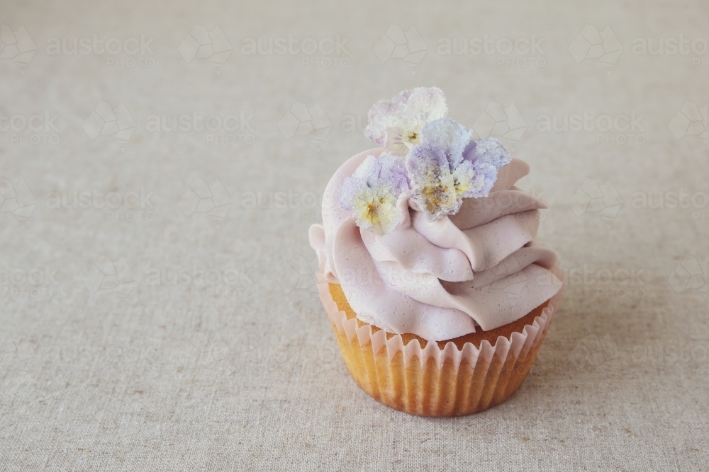 Purple cupcake with sugared edible flowers - Australian Stock Image