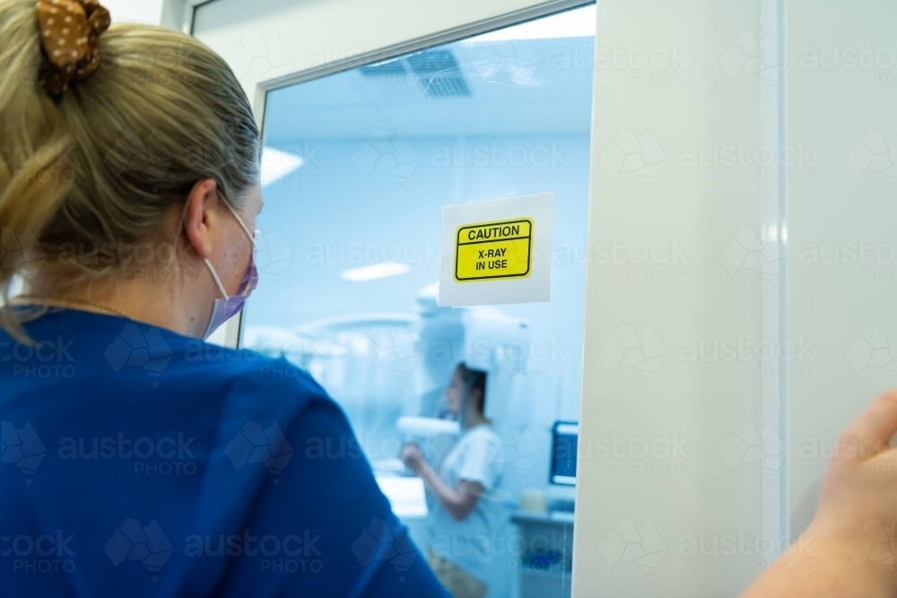 Radiography operator watching dental OPG X-ray being taken on young woman - Australian Stock Image