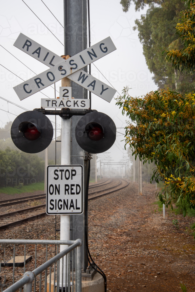 Railway crossing sign at a level crossing in Brighton, Adelaide on a foggy day - Australian Stock Image