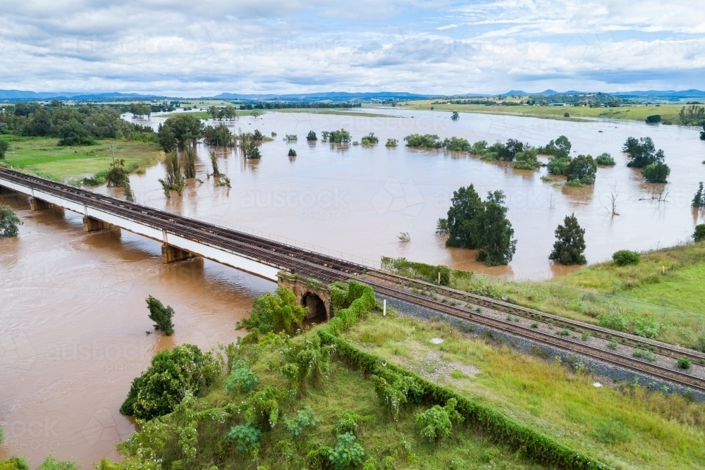 Railway line bridge over flooding Hunter River near Singleton during flood - Australian Stock Image