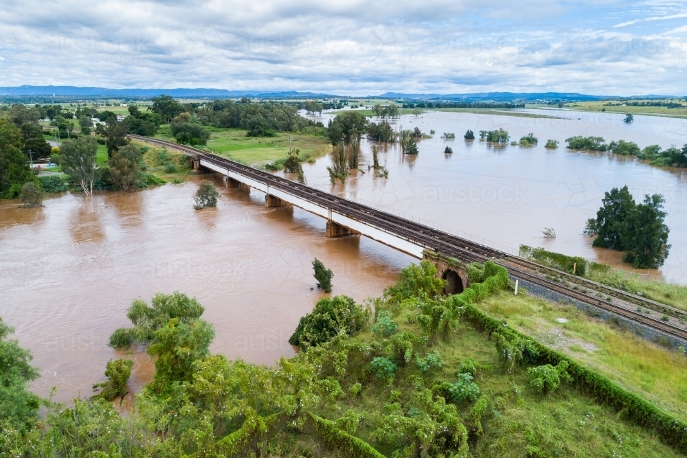 Railway line bridge over flooding Hunter River near Singleton during flood - Australian Stock Image