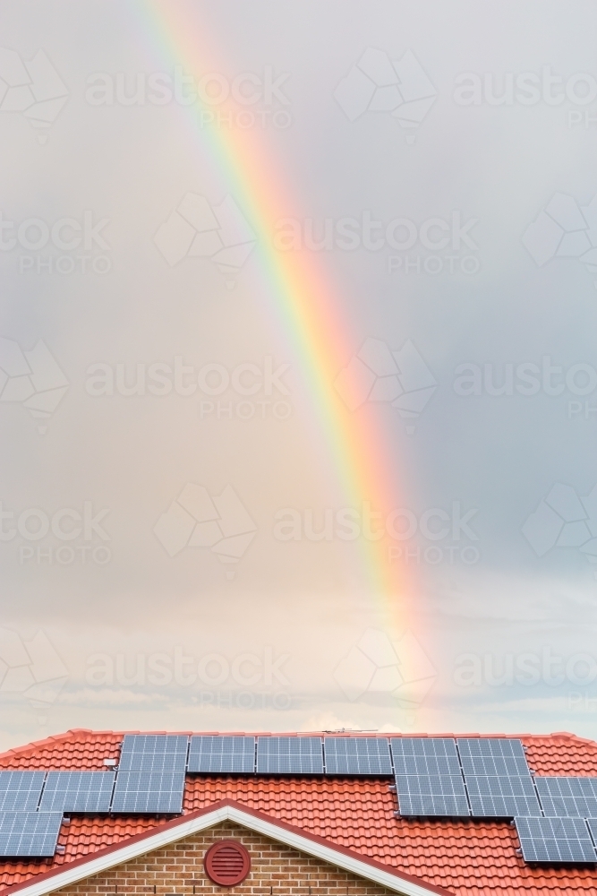 Rainbow over roof of house with solar panels shining after rain storm - Australian Stock Image