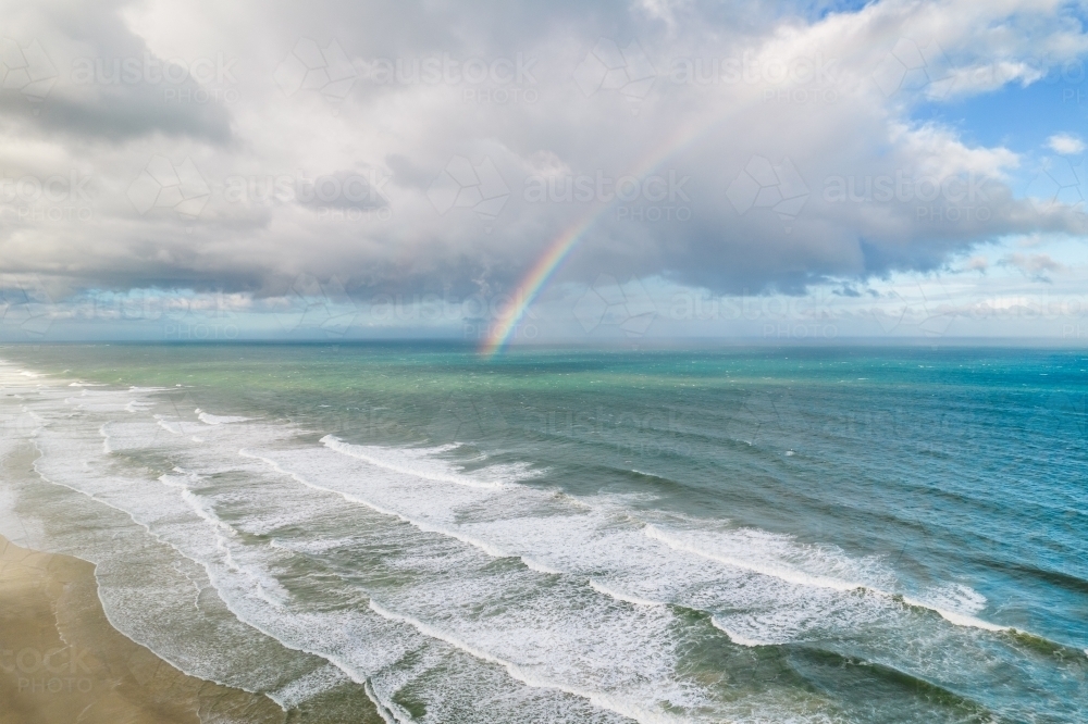 Rainbow setting along the ocean on Gold Coast coastline - Australian Stock Image