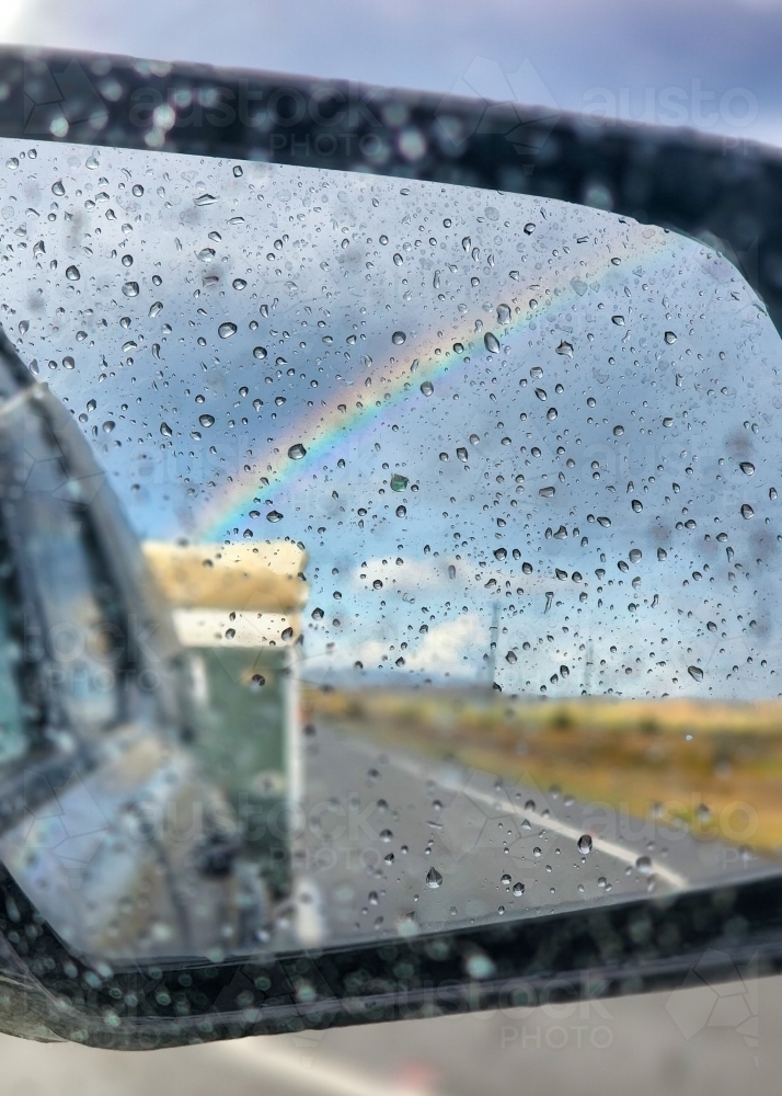 Raindrops on side mirror of car with view of caravan and rainbow - Australian Stock Image